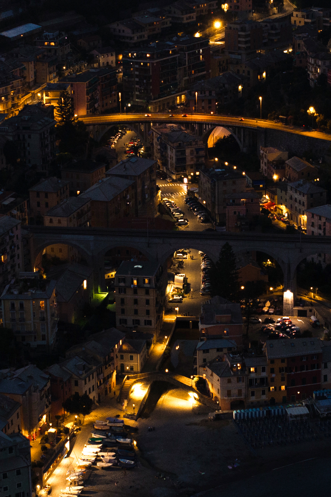 Aerial night view of Bogliasco with illuminated streets, bridges, and coastal houses in Liguria, Italy