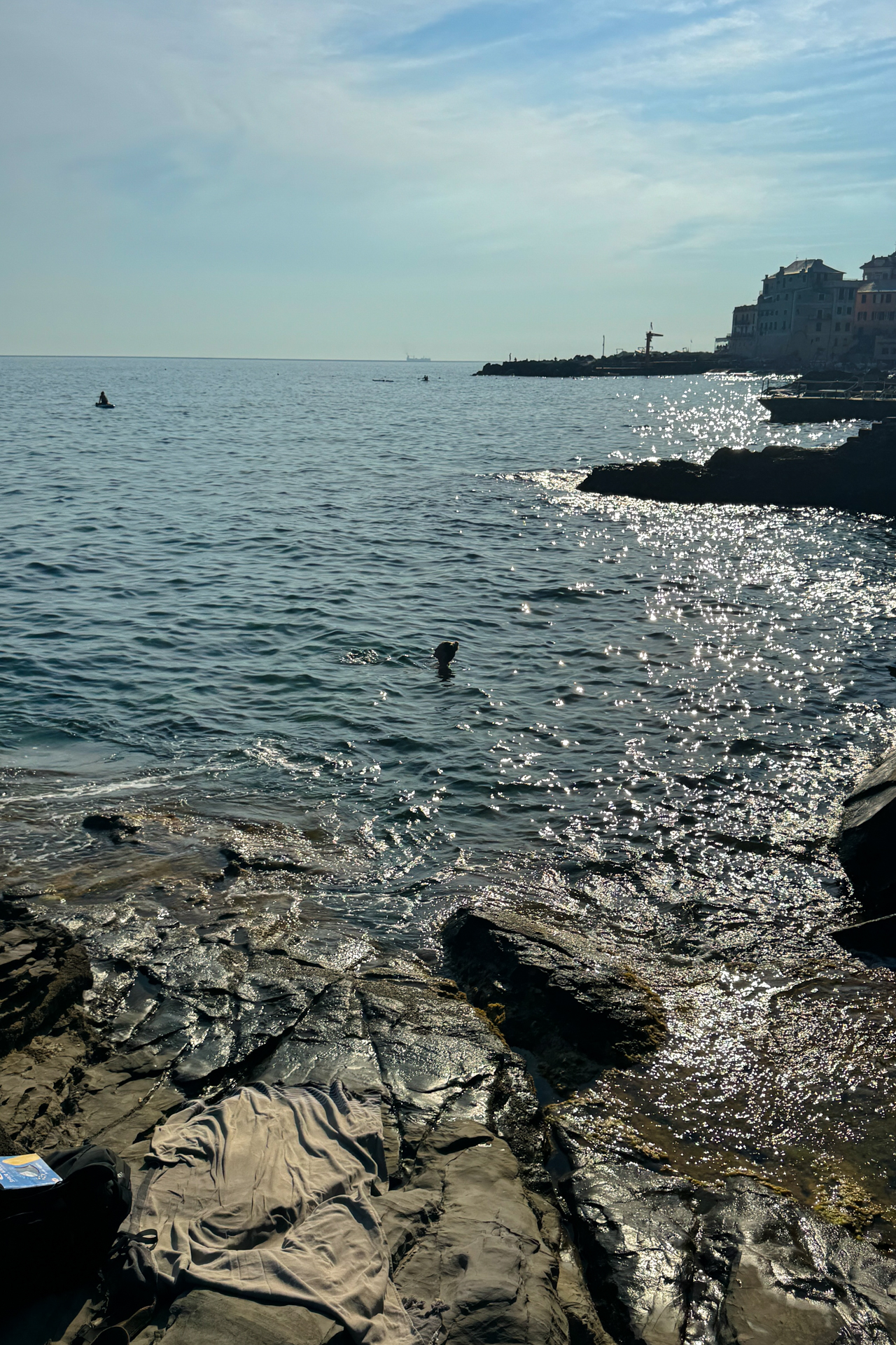 Rocky coastline of Bogliasco named Scogliera di Pontetto with people swimming in the sea