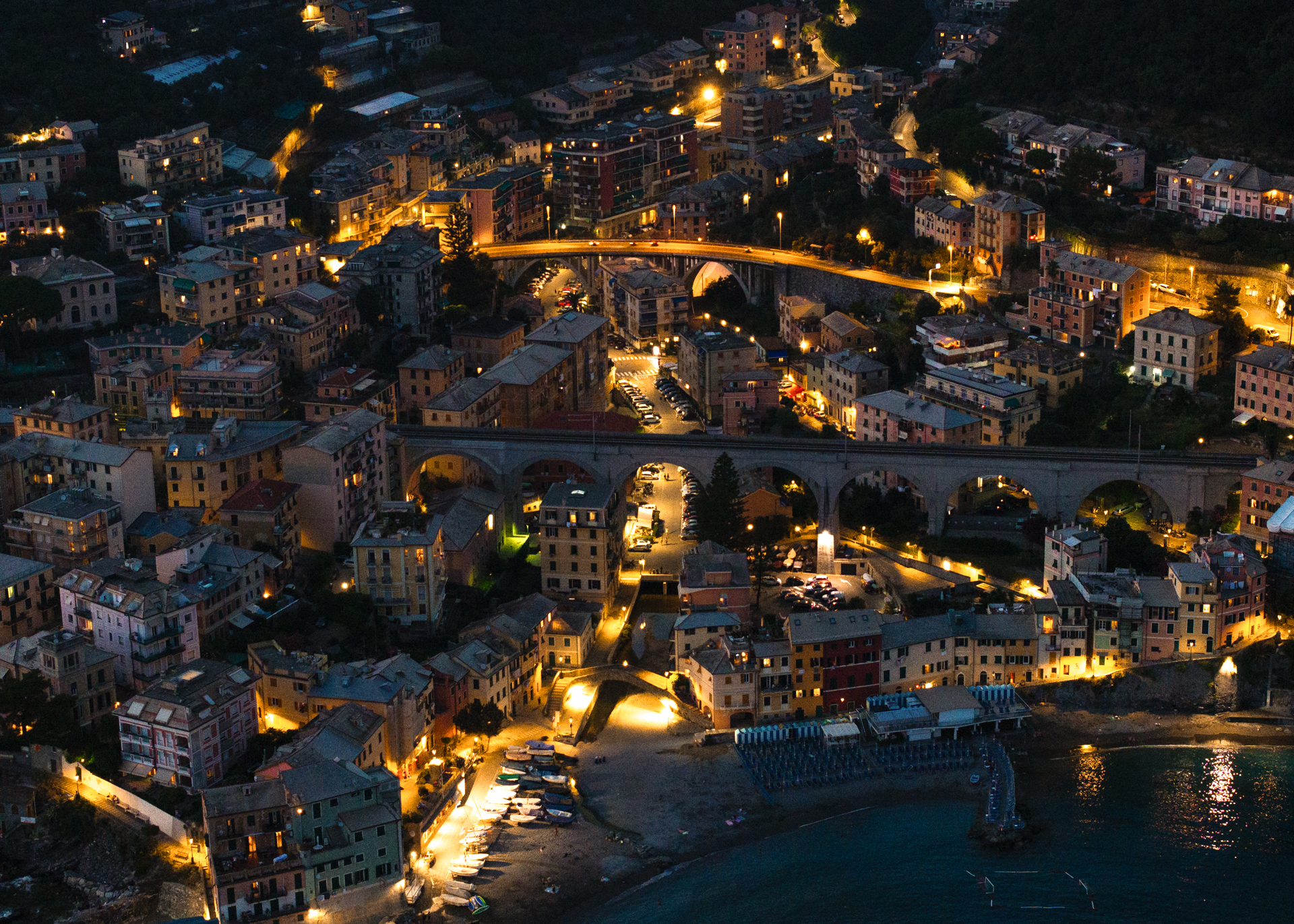 Aerial night view of Bogliasco with illuminated streets, bridges, and coastal houses in Liguria, Italy