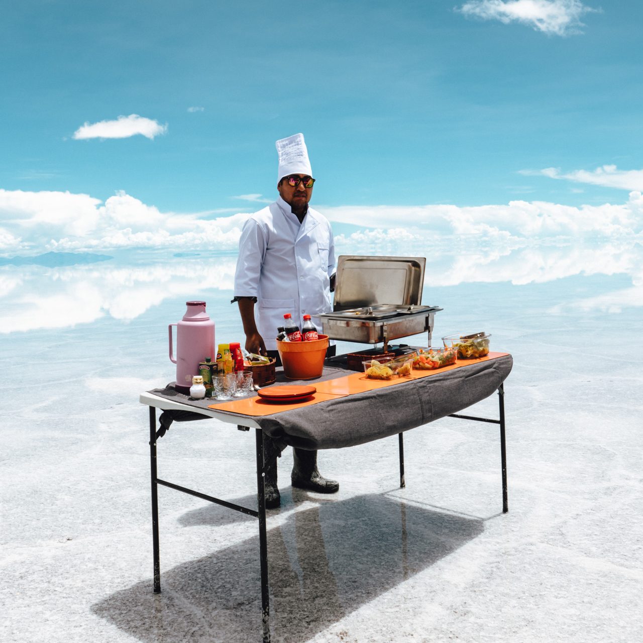 Food in Bolivia Chef cooking and serving food on Uyuni Salt Flats under blue sky, Bolivia