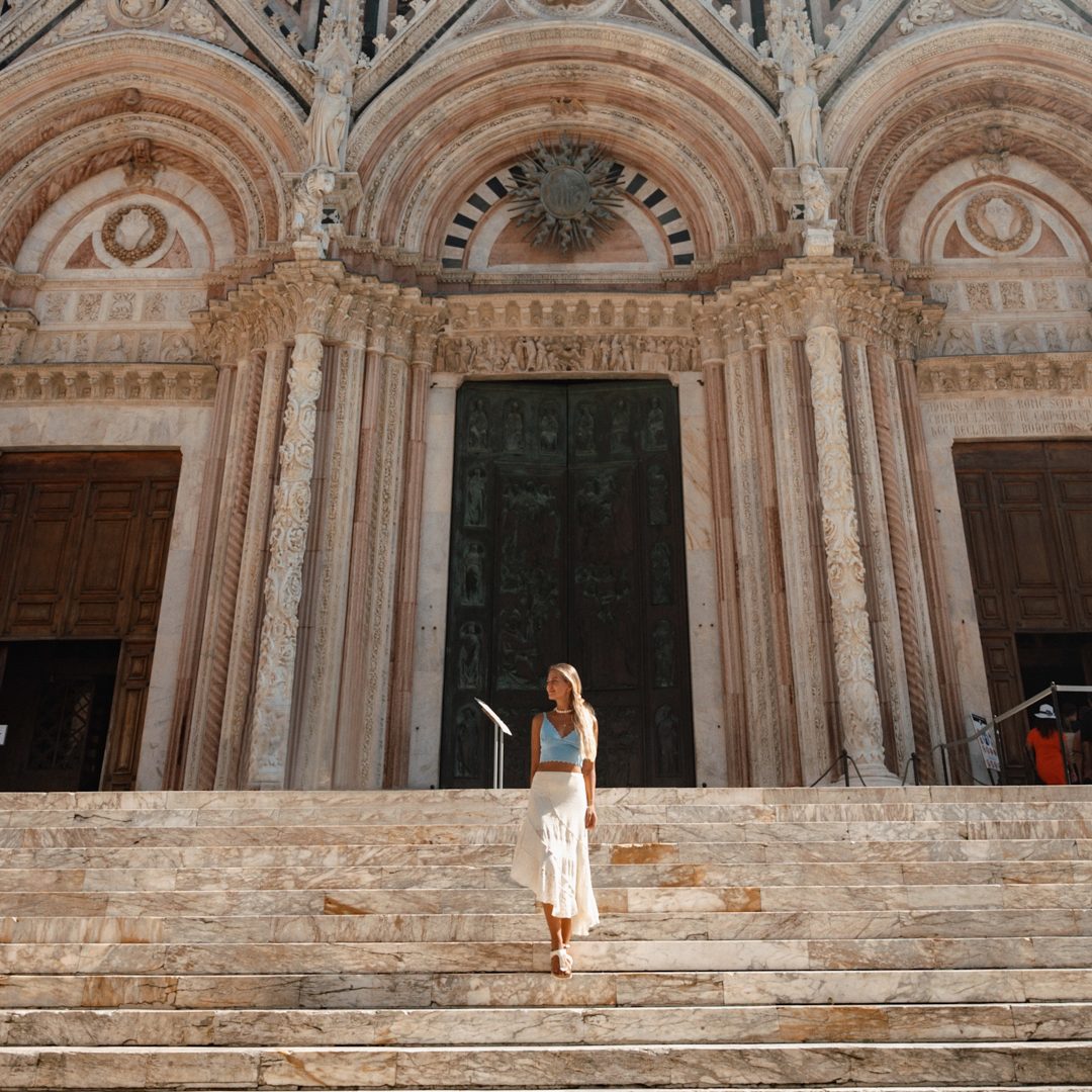 Traditions in Itay Traveler standing on the steps of Siena Cathedral in Tuscany, Italy.