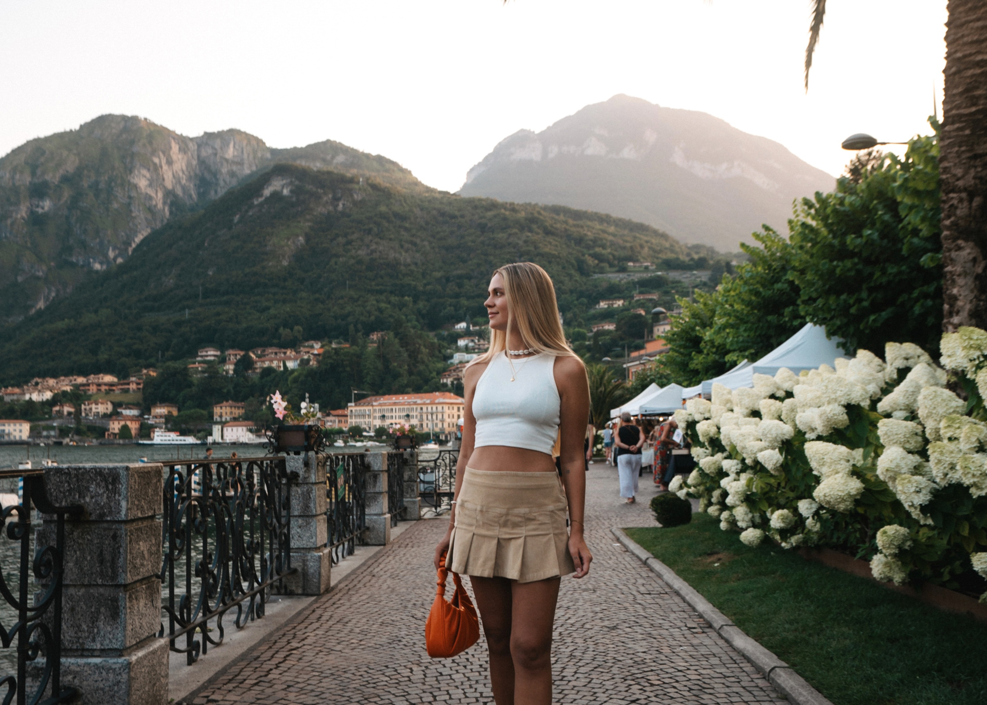 Menaggio lakeside promenade at sunset, surrounded by hydrangeas and views of the mountains on Lake Como, Italy.