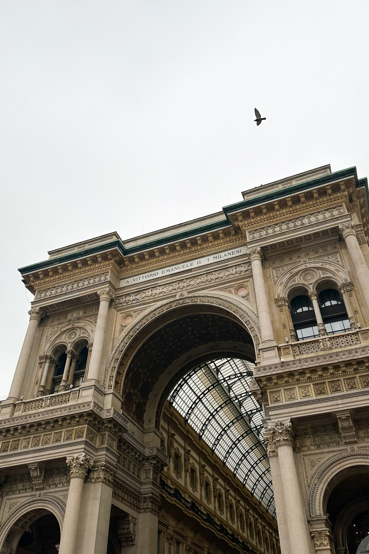 Exterior archway of Galleria Vittorio Emanuele II in Milan with bird flying above
