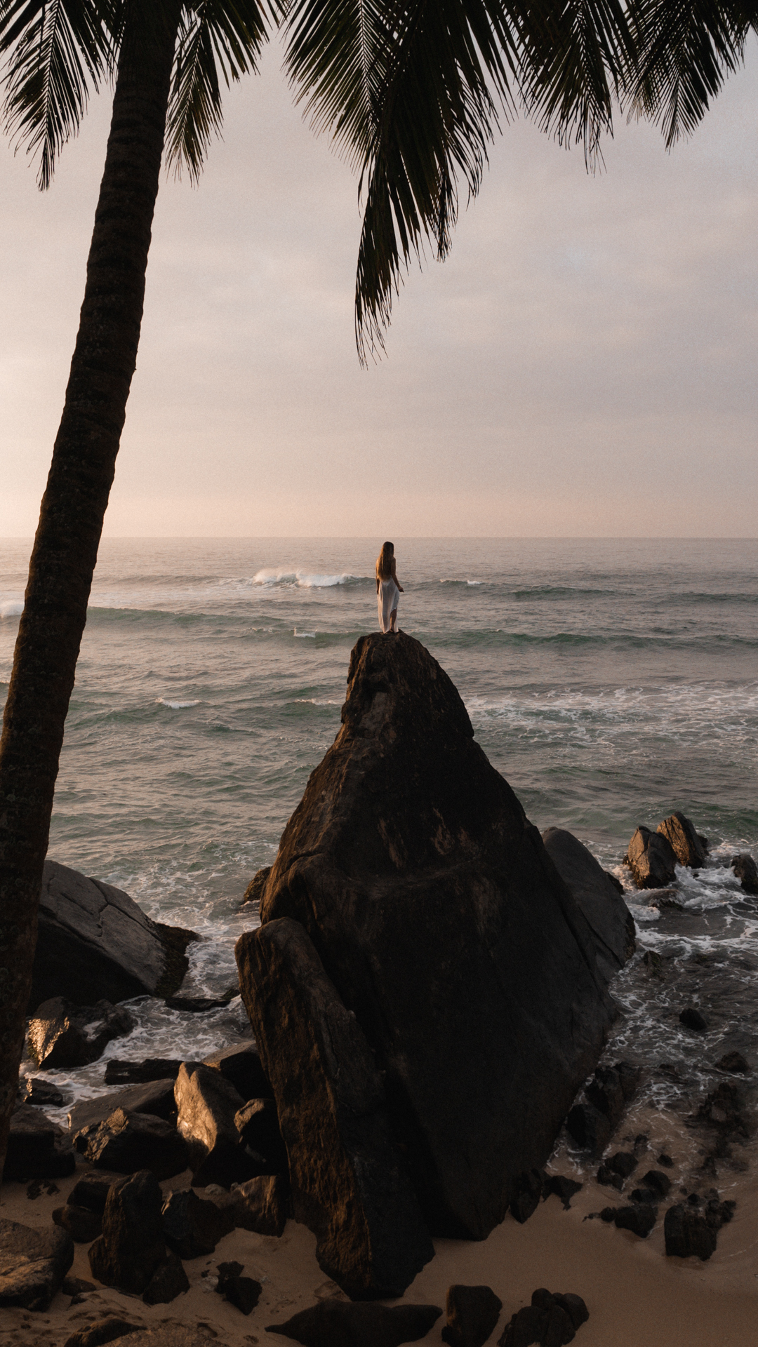 Unawatuna Silhouette of a woman standing on a rock by the ocean at sunset in Unawatuna, Sri Lanka