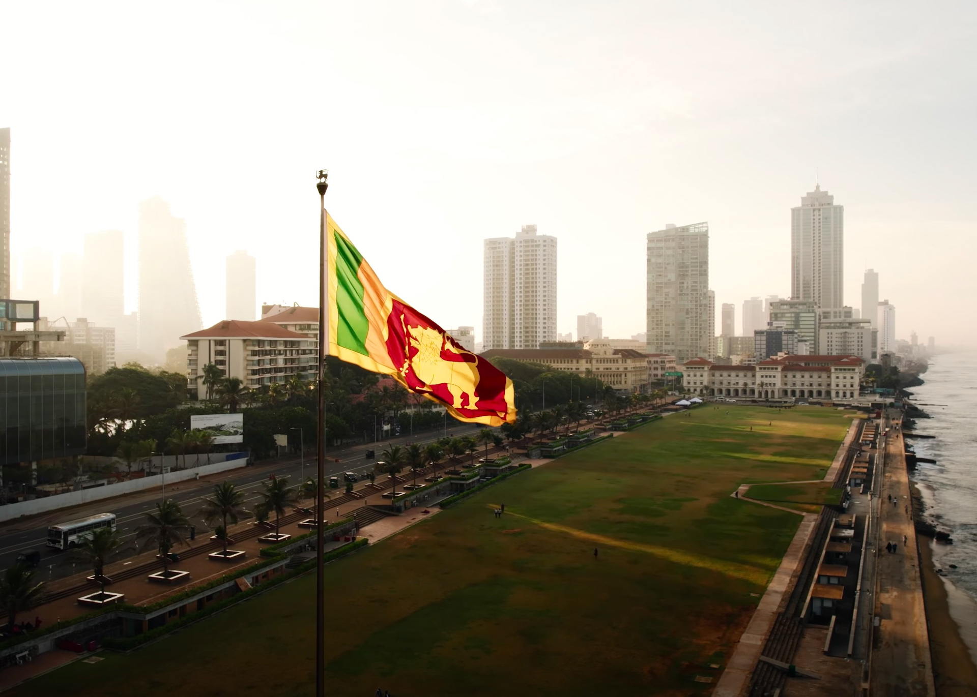 Sri Lankan flag waving high at Galle Face Green with Colombo skyscrapers in the background.