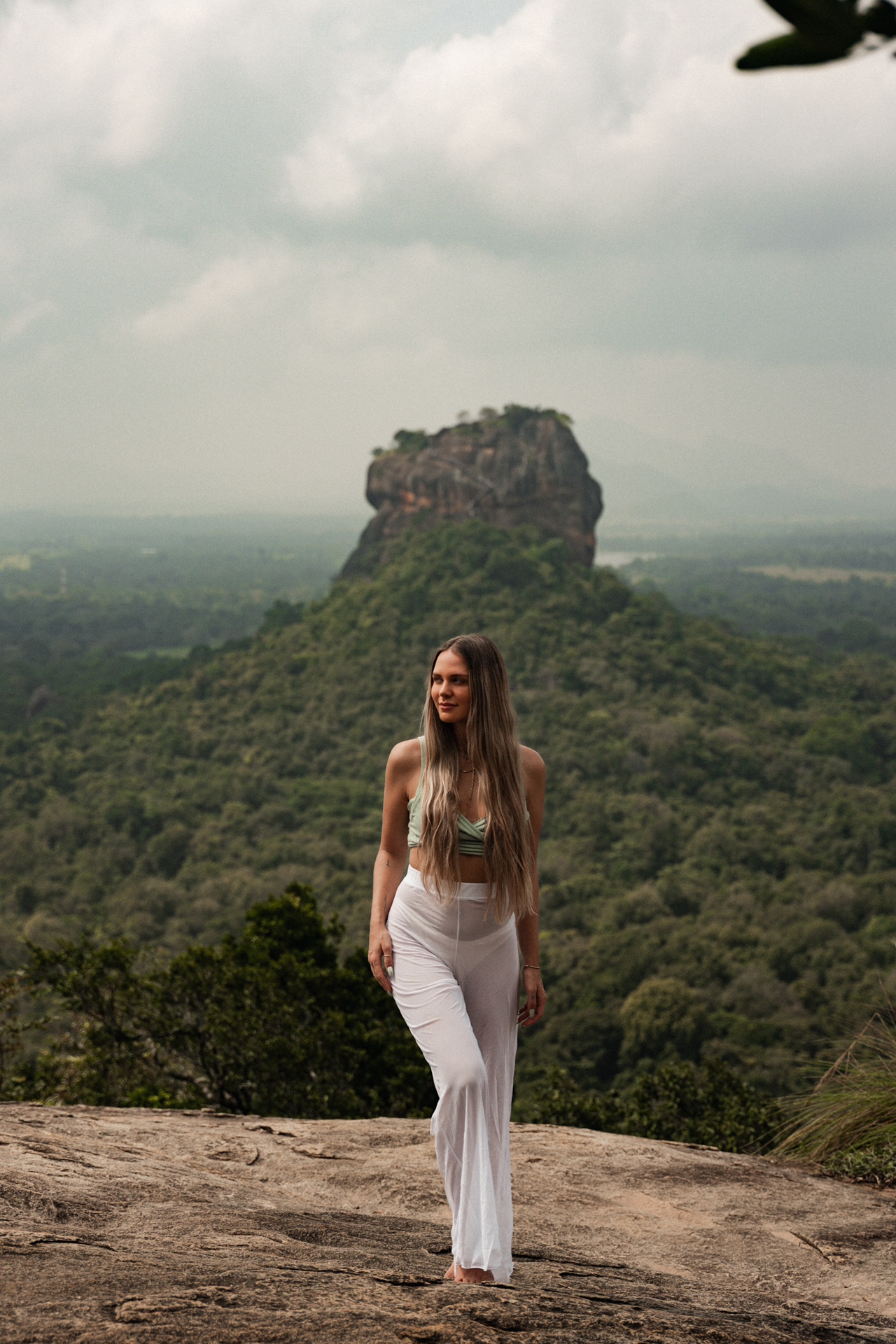 Traveler standing on pidurangala rock with Sigiriya Rock Fortress in the background.