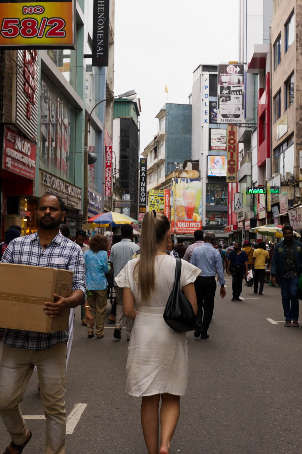 Busy Pettah Market street in Colombo with people shopping among colorful signs and stalls.