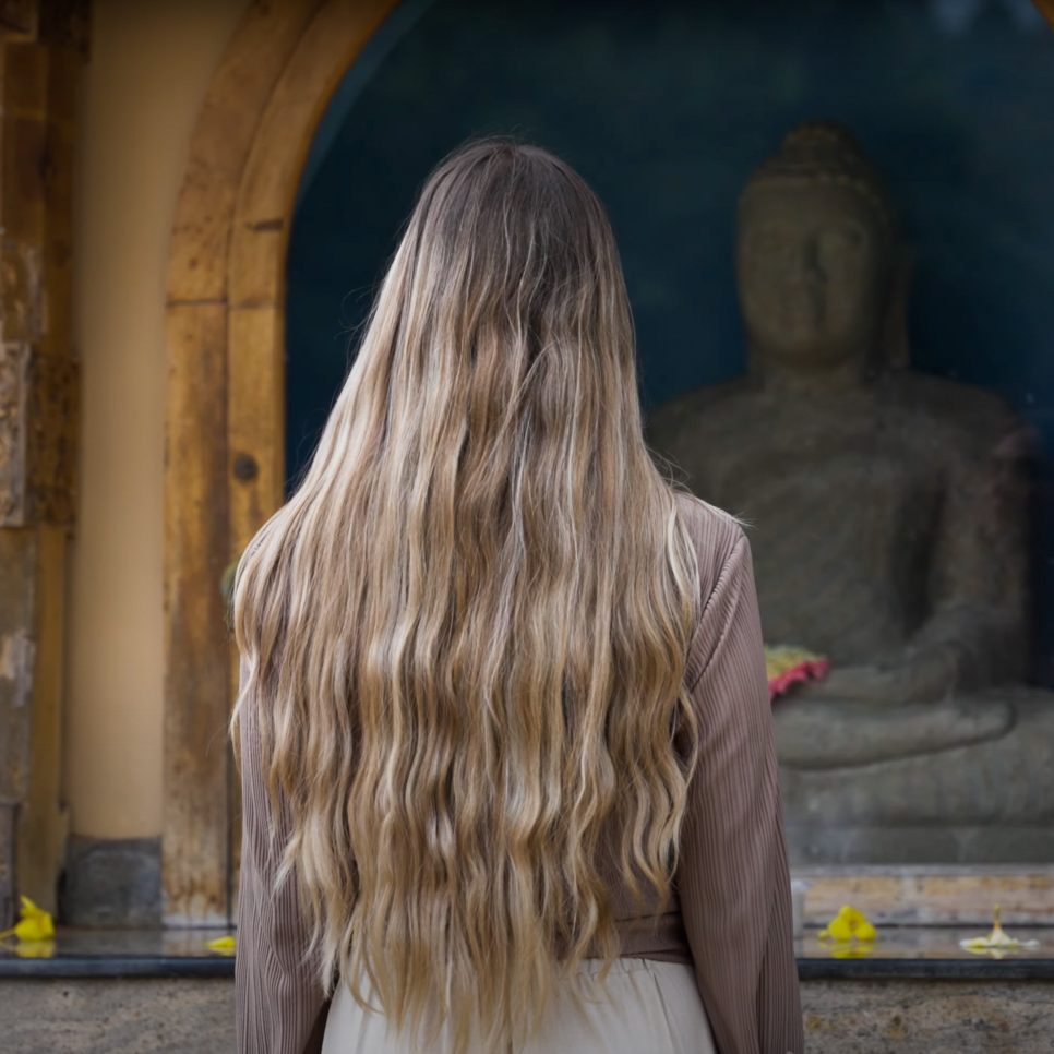 Culture in Sri Lanka Woman standing in front of a stone Buddha statue the Temple of the Tooth in Kandy, Sri Lanka