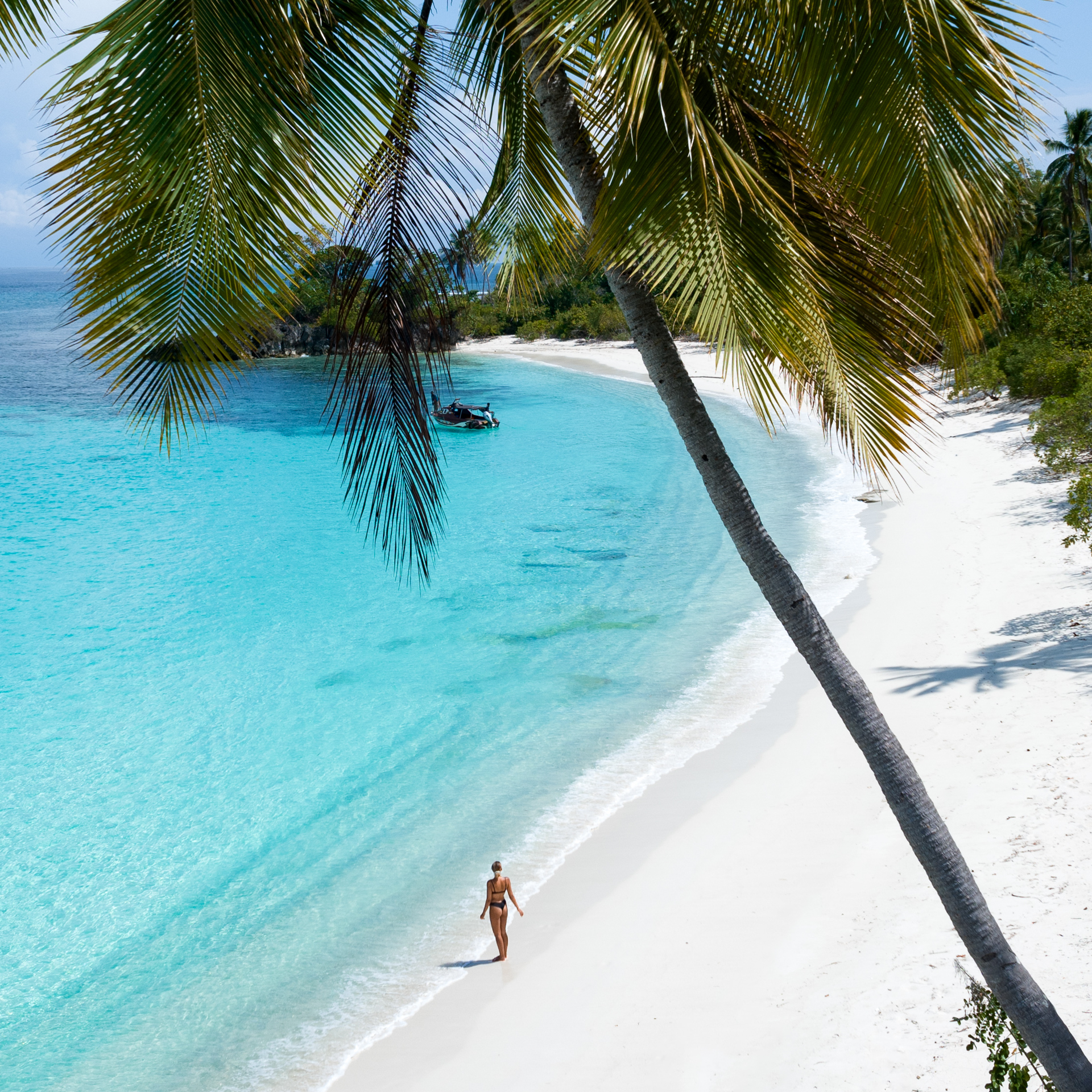 Woman walking on pristine white sand beach on Banggai Laut, Sulawesi