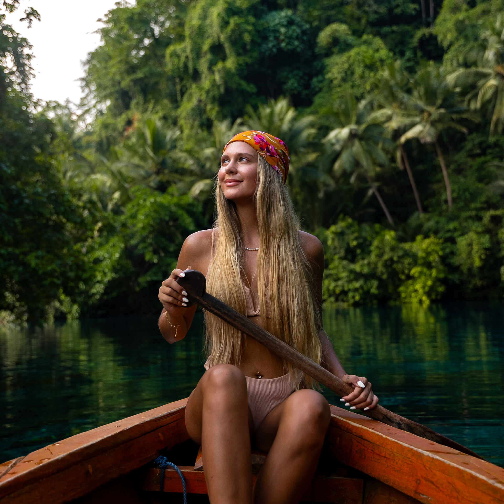 Woman paddling a wooden boat on crystal-clear water Paisu Pok Lake on the Banggai Islands.