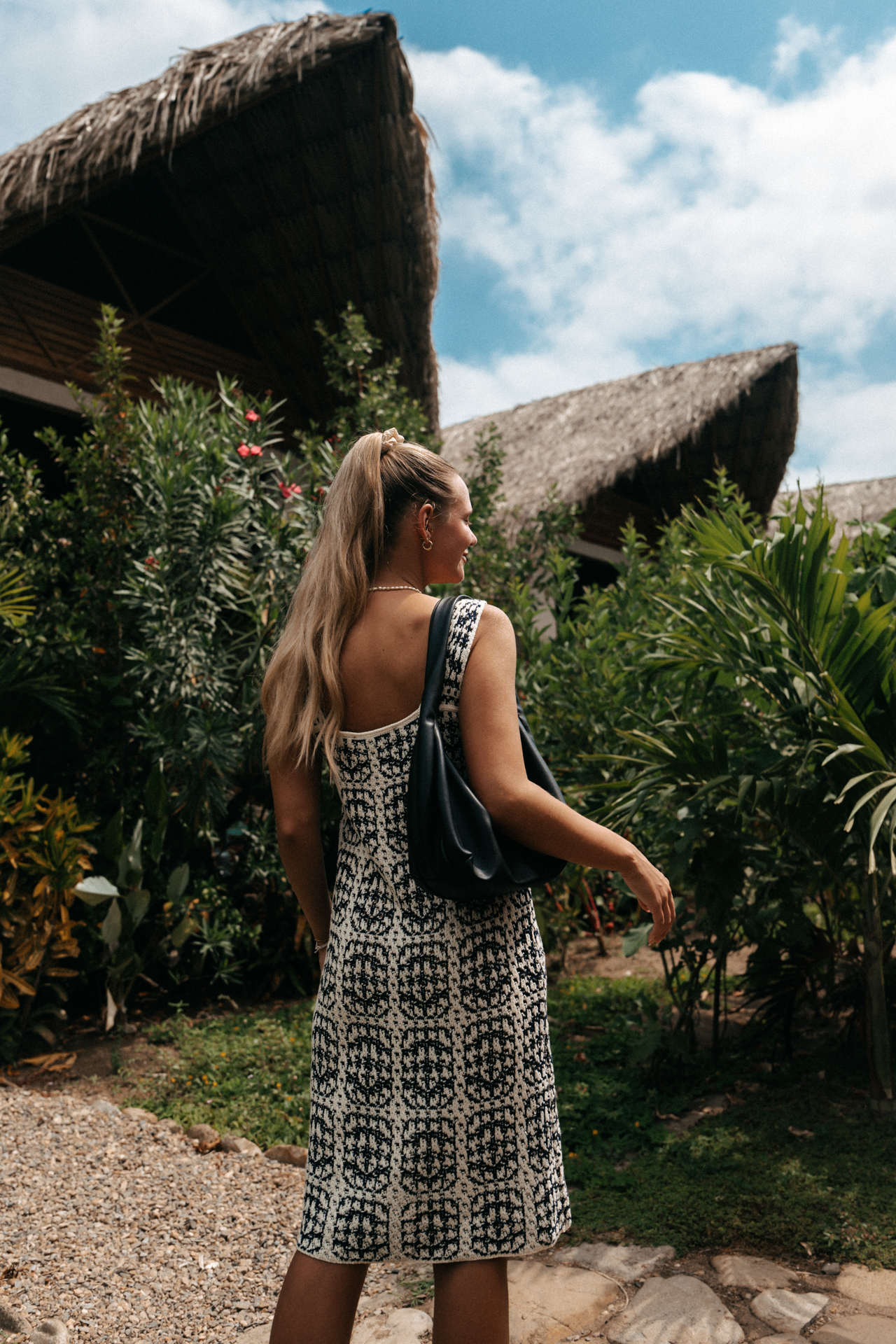 Palomino Woman walking past tropical plants and traditional thatched-roof huts on Colombia’s Caribbean coast in Palomino.