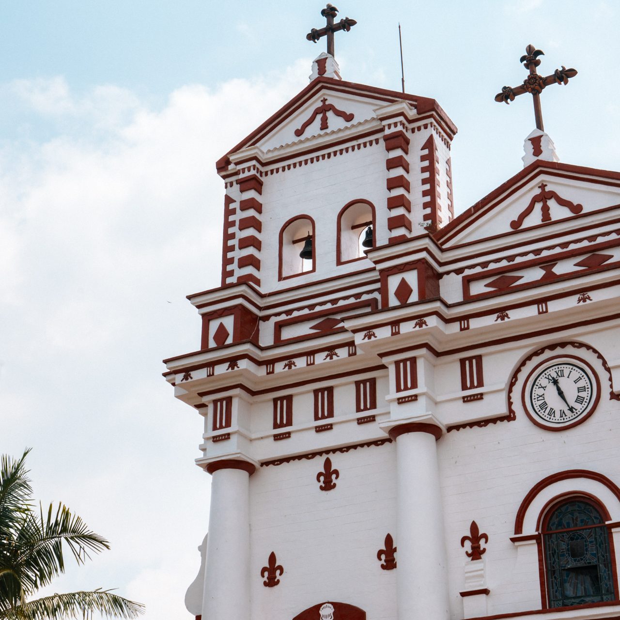 Traditions in Colombia Colonial white and red church facade with clock and crosses in Guatapé, Colombia.
