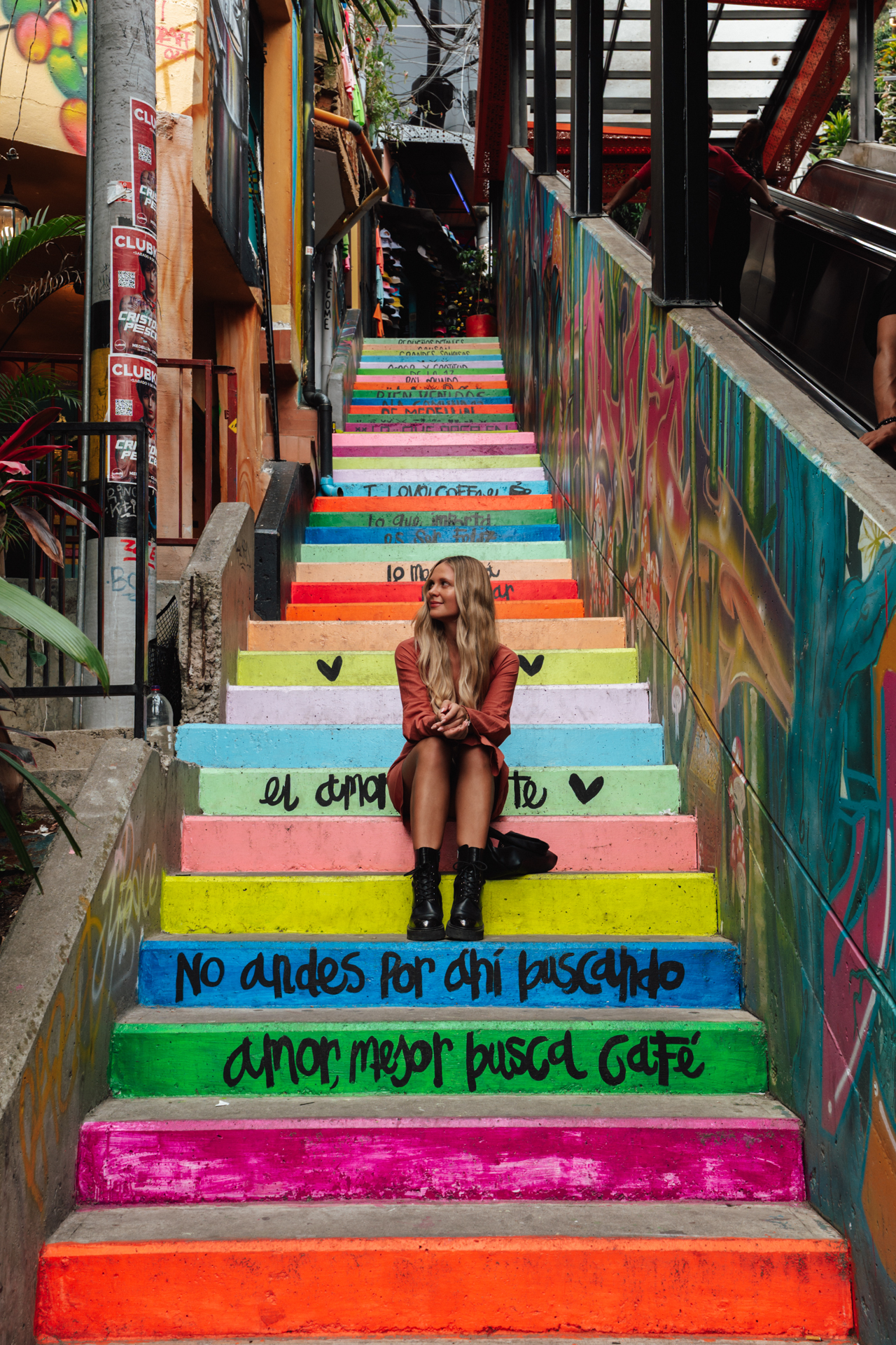 Medellín Woman sitting on colorful painted stairs in Comuna 13, a vibrant neighborhood in Medellín, Colombia.