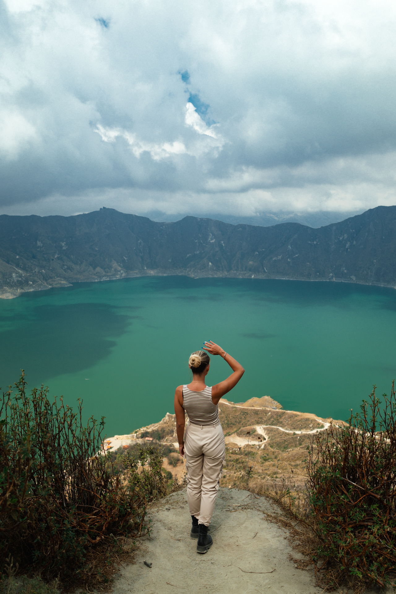 Quilotoa Crater Woman overlooking the turquoise waters of Quilotoa Crater Lake in Ecuador, surrounded by dramatic volcanic mountains.