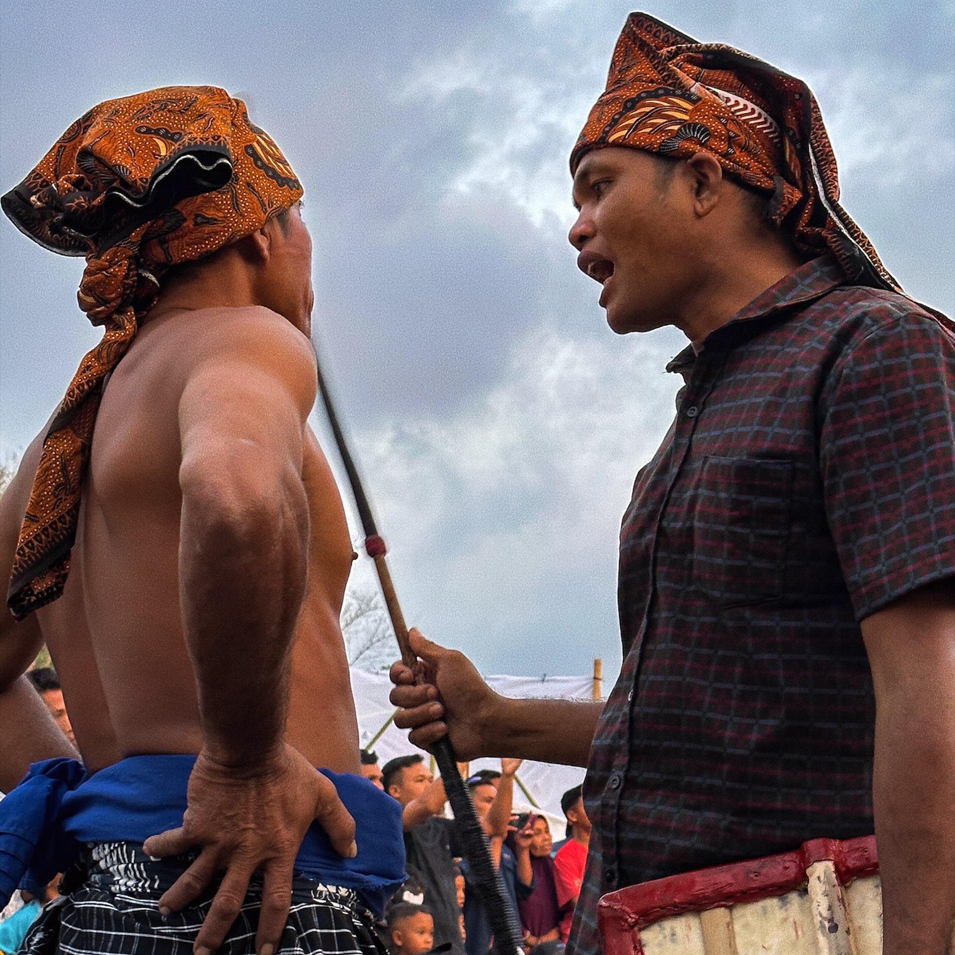 Traditions in Indonesia Two men in traditional attire prepare for a cultural performance in Lombok. Stick fight.