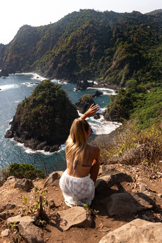 Lombok Woman enjoying a scenic view over dramatic cliffs and turquoise ocean waves in Lombok, a highlight of Indonesia travel.
