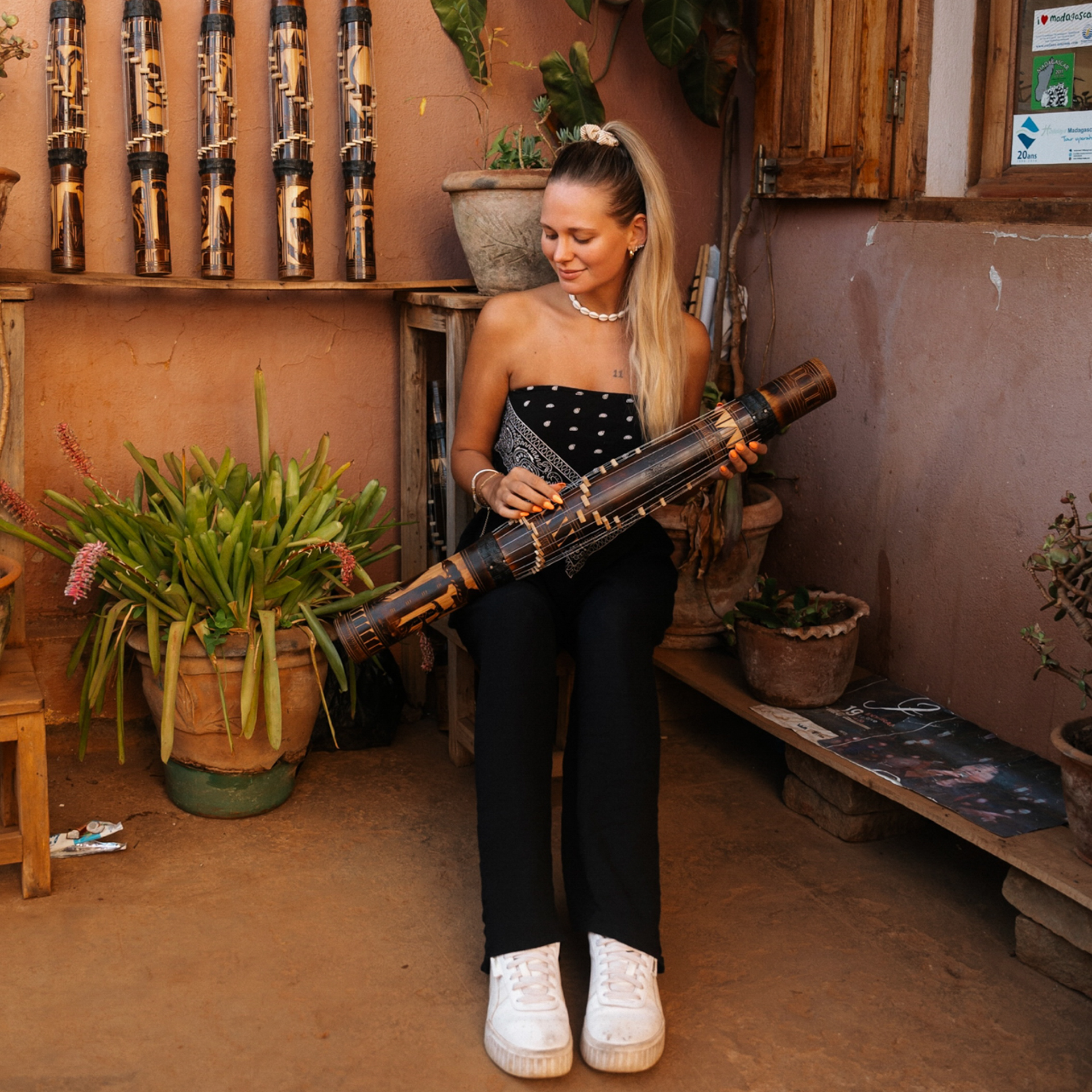 Culture in Madagascar Woman sitting with a handmade Malagasy bamboo instrument in a rustic shop in Antsirabe.