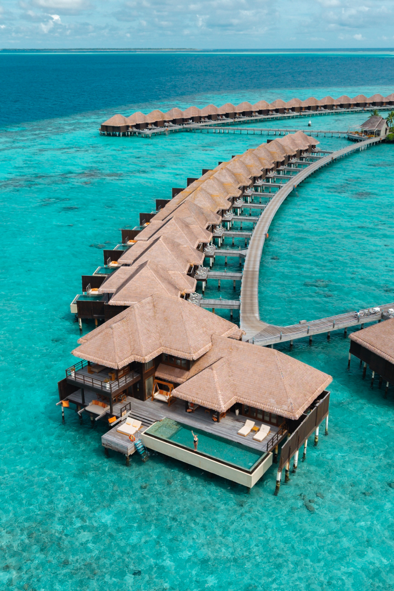 Ayada Resort Aerial view of Yada Maldives, overwater villas curving across the turquoise lagoon.