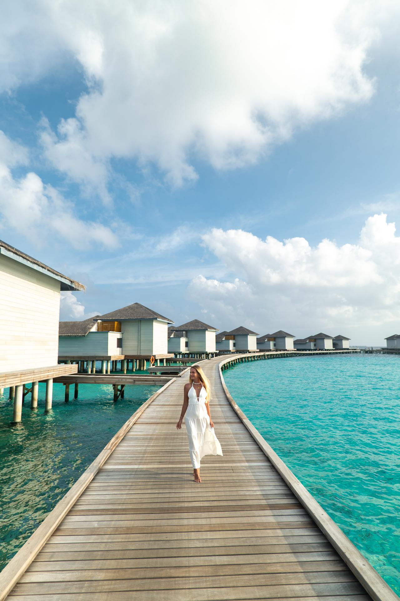Raffles Resort Walking along the wooden boardwalk at Raffles Maldives, surrounded by overwater villas.