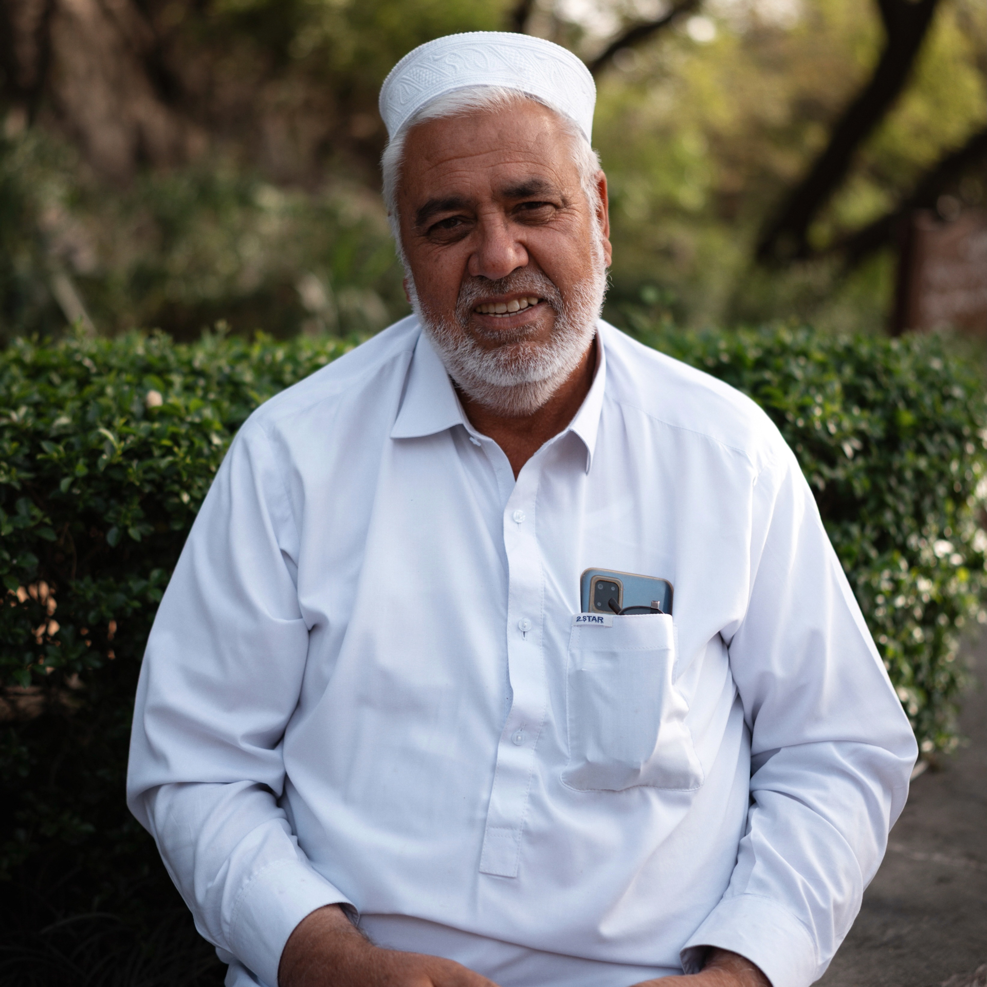 Traditions in Pakistan Portrait of an elderly Pakistani man in white shalwar kameez sitting outdoors