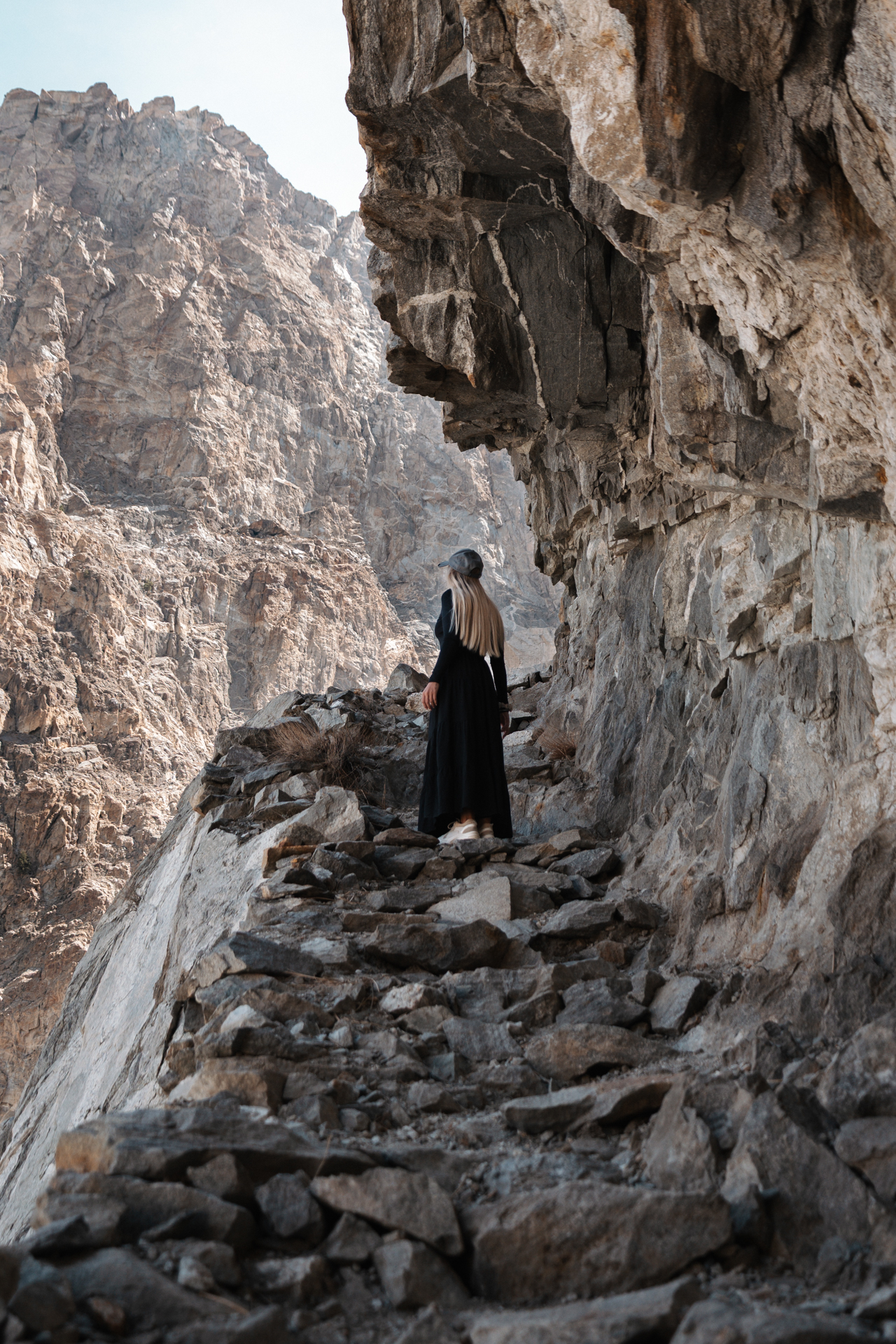Hunza Woman walking along a rocky mountain trail under steep cliffs in Hunza, Gilgit-Baltistan, I in Pakistan.