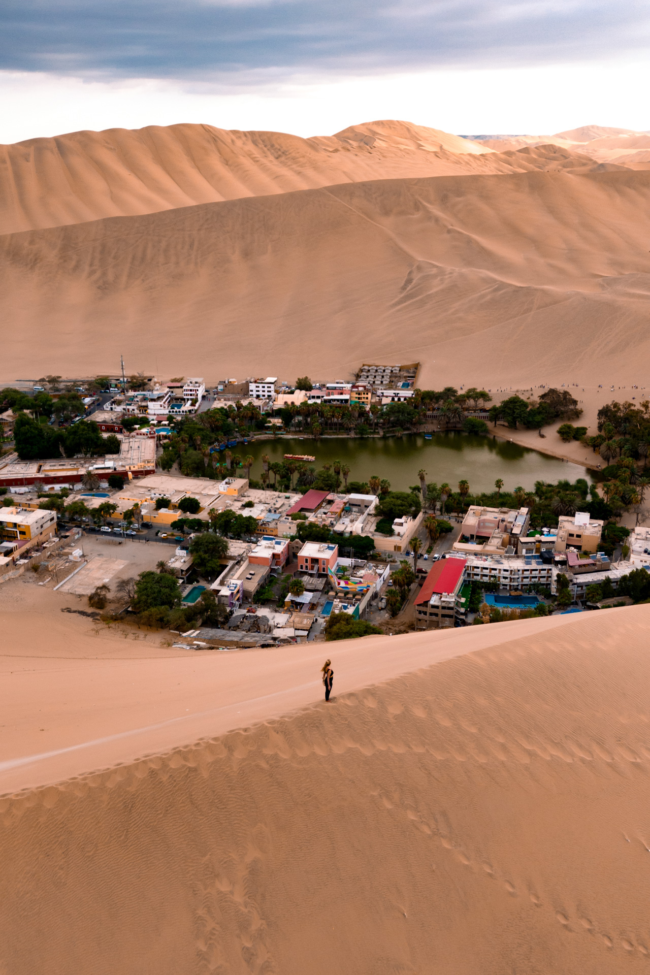 Huacachina Drone photo of a woman standing above Huacachina, Peru in the desert