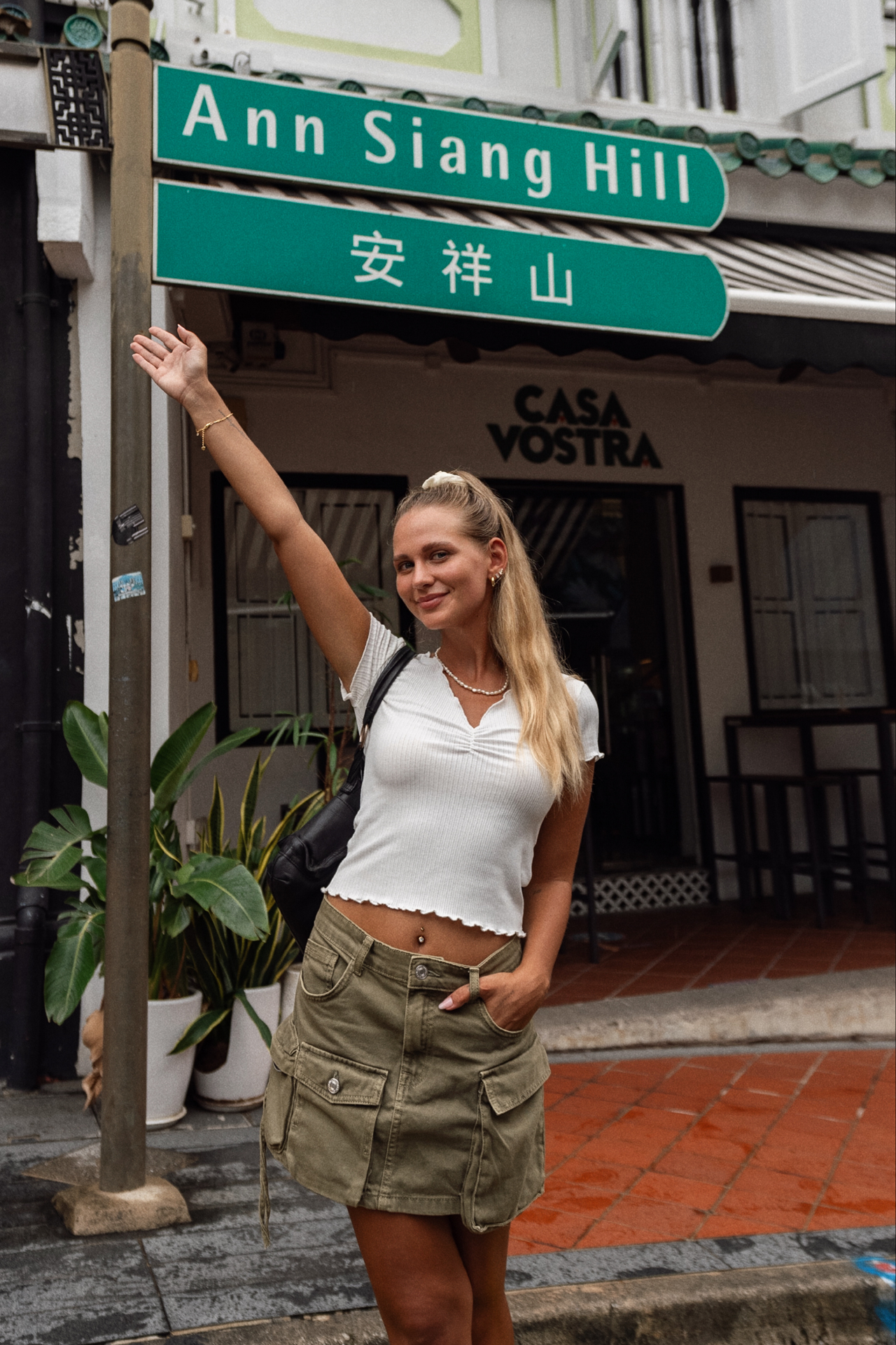 Ann Siang Hill Traveler pointing at Ann Siang Hill street sign in Singapore.