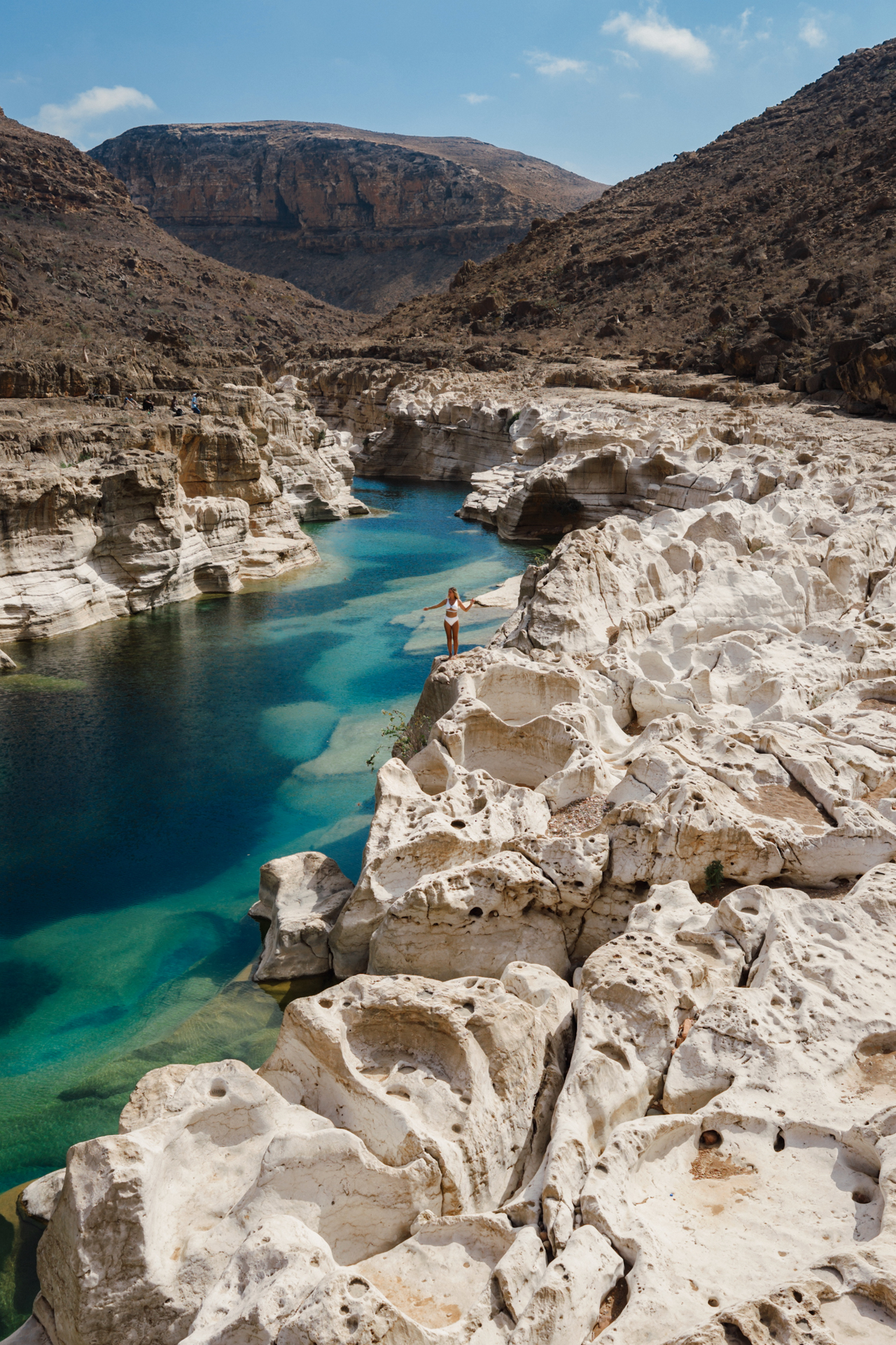 Wadi Kalissan Woman standing on white limestone cliffs at Wadi Kalissan above a turquoise pool in Socotra.