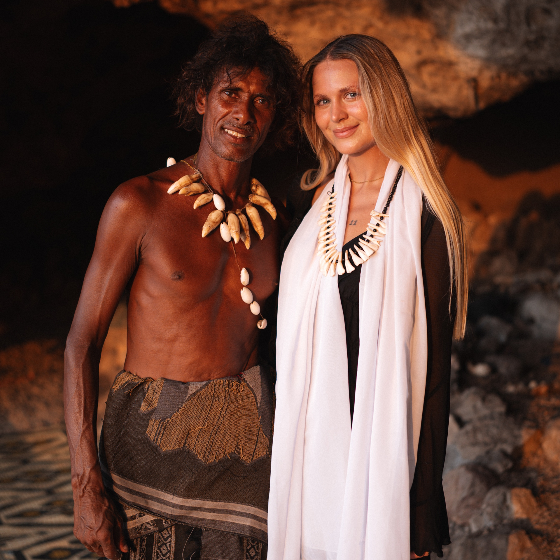 Culture in Socotra Cave man with shell necklace and tourist woman at Socotra cave during sunset.